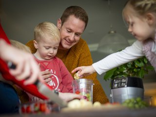 Rob, who has CML, makes a smoothie with a young family, placing fruit into a blender.