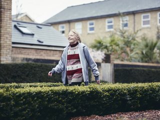 An older woman Eric strides happily down a suburban street on her way somewhere.