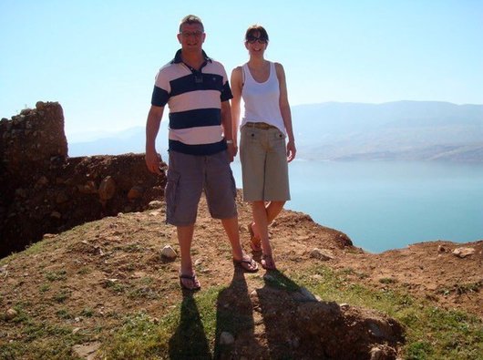 Steve, who lived with MPN, stands smiling on top of a sunny cliff with his wife Jane.