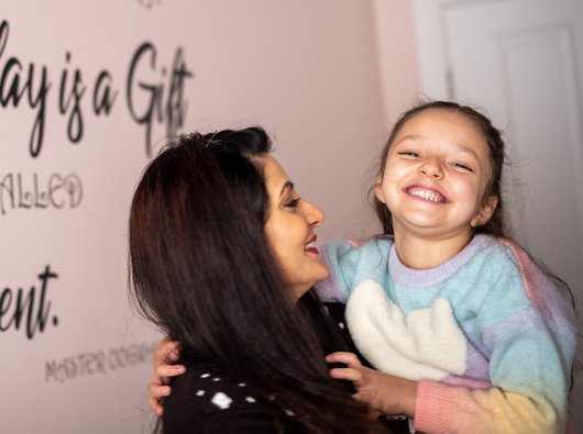 Mia laughing with mum as she picks her up.