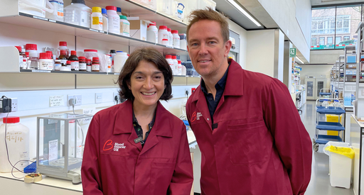A man and a women in Blood Cancer UK lab coats smiling at the camera