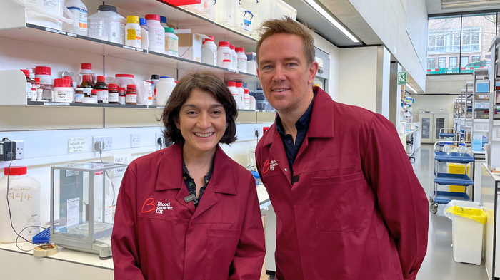 A man and a women in Blood Cancer UK lab coats smiling at the camera