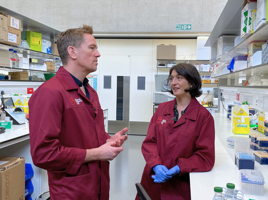 Female researcher showing a man things in a lab.