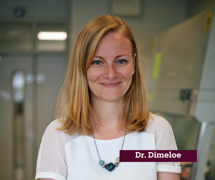 Dr Sarah Dimeloe stood in the lab smiling.