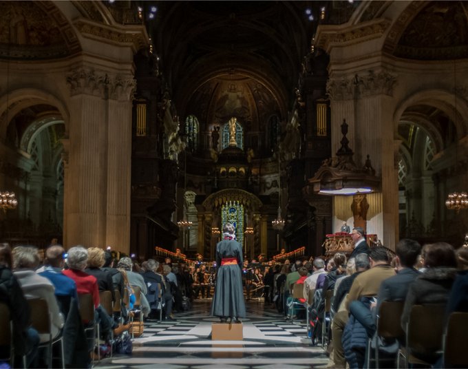 The inside of St Paul's Cathedral, lit up in Christmas lights with a full audience of people in their seats.