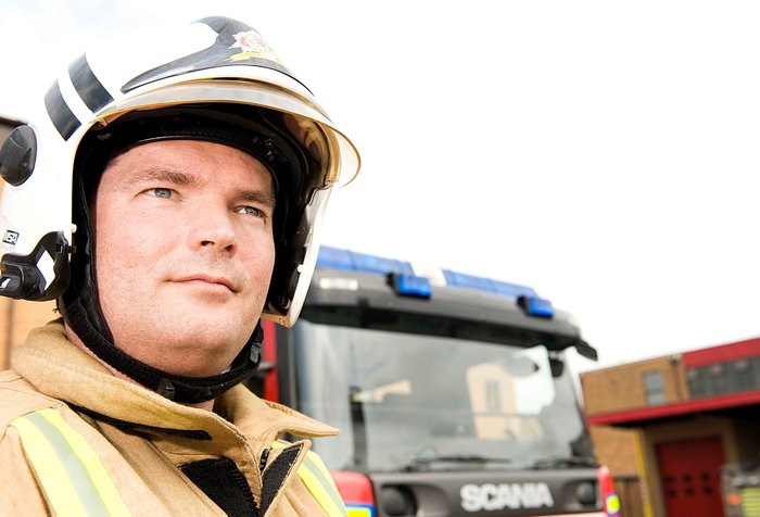 Ally wearing fire uniform, standing in front of a fire engine