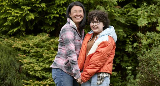 Alyssa, who had successful treatment with CAR T-cell therapy at age 13. She's pictured in a garden with her mum, holding hands and smiling.