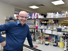 Professor Chris Bunce stood in the lab smiling.