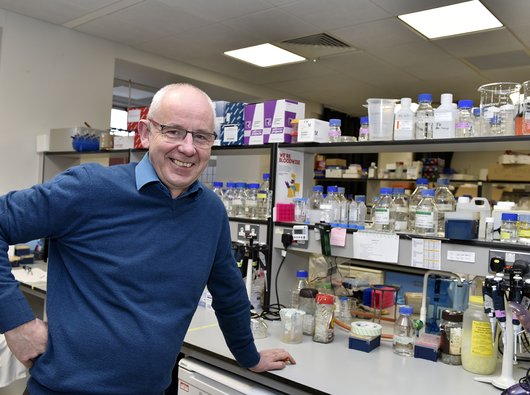 Professor Chris Bunce stood in the lab smiling.