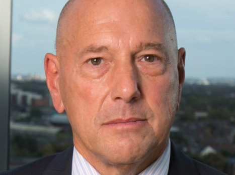 A headshot of Claude Littner, looking seriously at the camera and wearing a suit and tie.