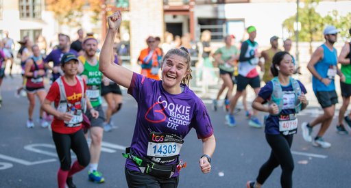 Female Blood Cancer UK runner celebrating with one arm in the air