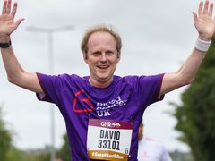 A runner crosses the line at the Great North Run 2022, with their arms in the air to celebrate