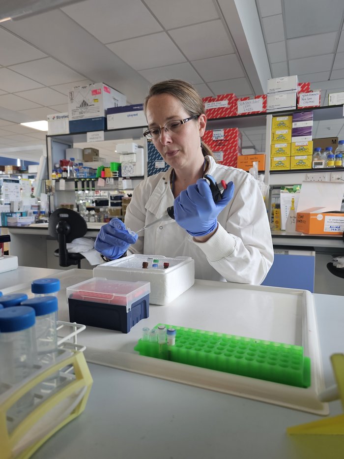 Dr Lisa Russell working in the lab, wearing a white lab coat.