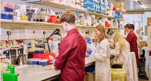 Researchers in a lab smiling in lab coats working