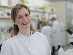 Dr Beth Payne standing in the lab smiling