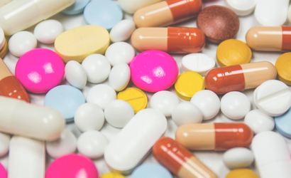 A selection of different white pills and colourful capsules close up.