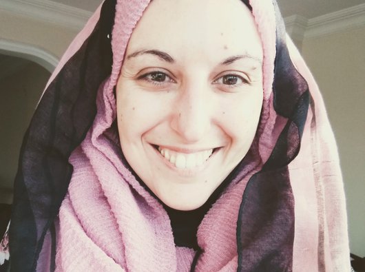 A selfie of a woman (Federica) smiling, wearing a pink and black headscarf