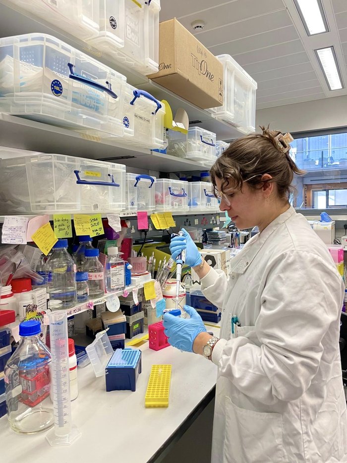 A lady wearing a white lab coating working away in the lab.