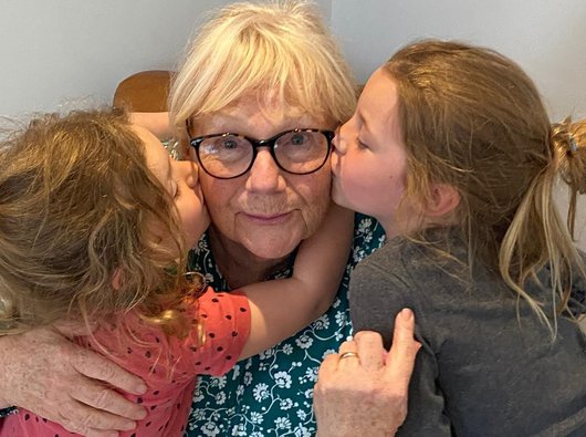 Gail, who's living with essential thrombocythaemia (ET), being hugged by two of her grandchildren.