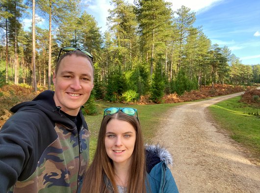 Grant, who had CAR T-cell therapy for blood cancer, standing next to his wife. They're outside in the countryside, with trees behind them.