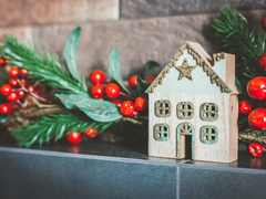 Close up photo of a Christmas display, with holly leaves and a small model wooden house.