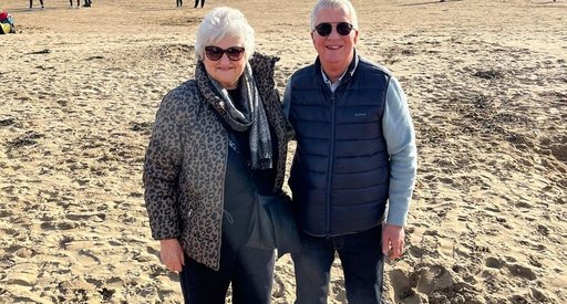 Jacqui and her husband walking on the beach on a sunny autumn day.