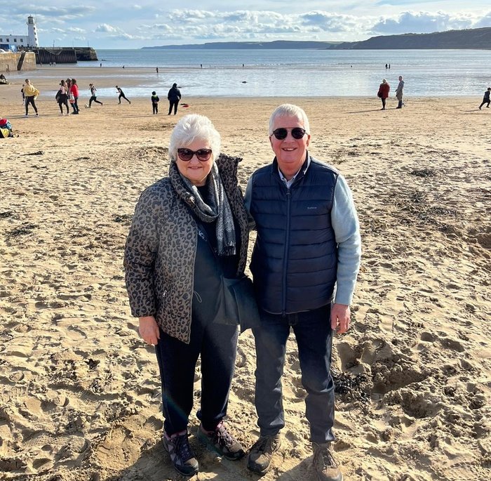 Jacqui and her husband walking on the beach on a sunny autumn day.