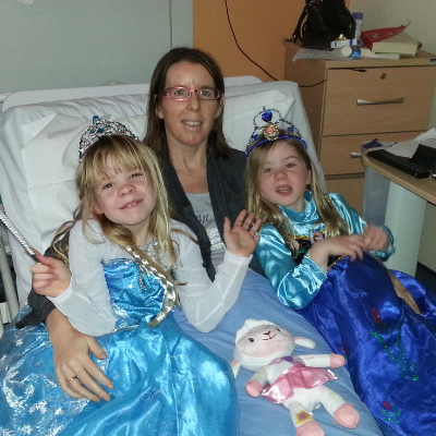 Jane Leahy, blood cancer patient, in a hospital bed with her daughters, dressed as princesses.