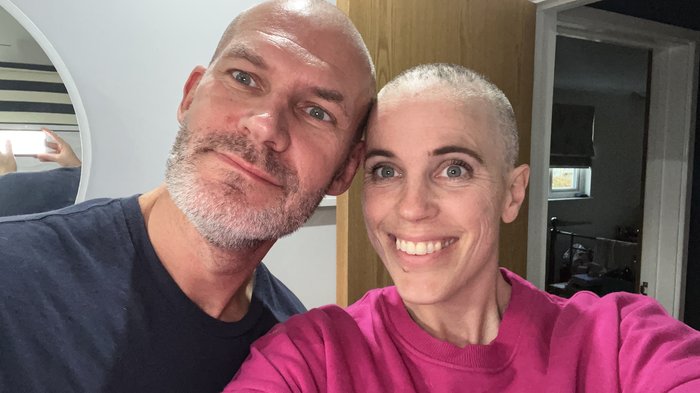 Jess, in remission from diffuse large B-cell lymphoma, smiling at the camera with her partner