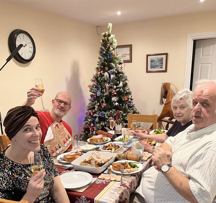 Jess, wearing a turban, with her partner and parents having a Christmas dinner