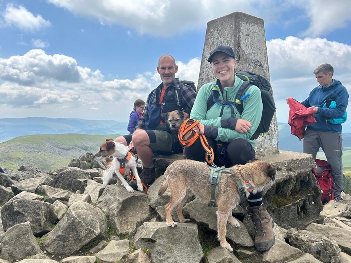 Jess at the top of a mountain with her partner and friends.