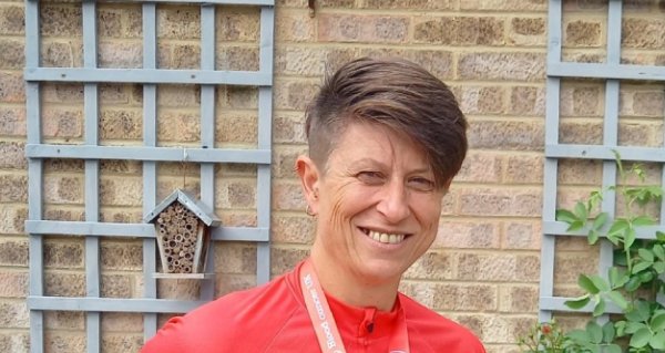 A female cyclist smiles holding their medal in front of their bike having completed the Ride London event