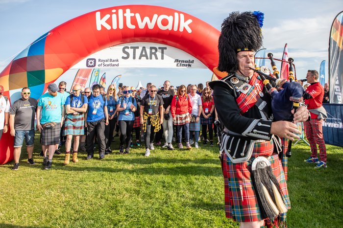 Bagpipes being played and walkers taking part in a Kiltwalk event in Scotland.