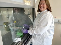 Professor Lesley Anderson stood up smiling as she is working on her research in the lab.