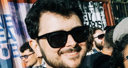 Matt living life in remission from blood cancer. He's smiling and looking happy at an outdoor event, with people in the background.