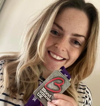 Female holding Blood Cancer UK medal close to the camera