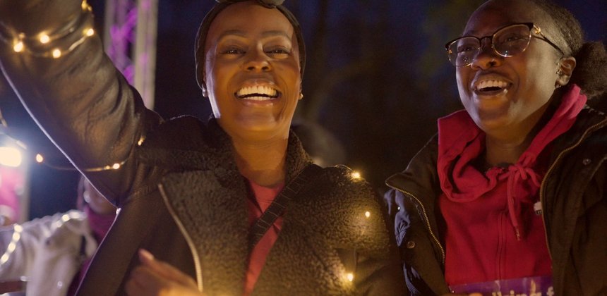 Nadine and friend laughing close up to camera with lights at Walk of Light Birmingham 2024