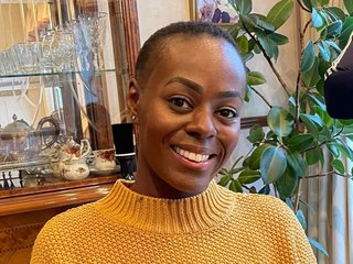 Nadine, wearing a yellow jumper and smiling