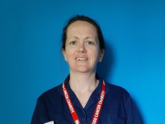 Alison, a blood cancer clinical nurse specialist, poses for a headshot in front of a blue background.