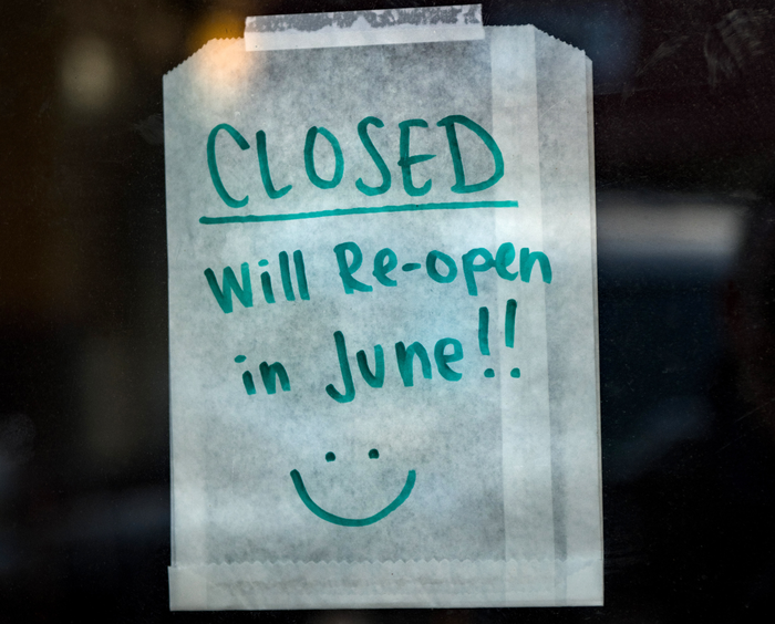 A sign taped to a window announcing a shop is shut and will re-open in June