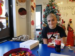 Ozzie, who lived with acute myeloid leukaemia (AML), sits at a table in a room with Christmas decorations.