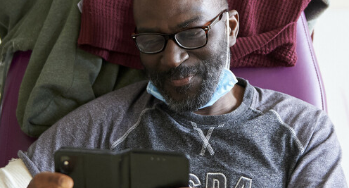 A man in a hospital chair is using his phone