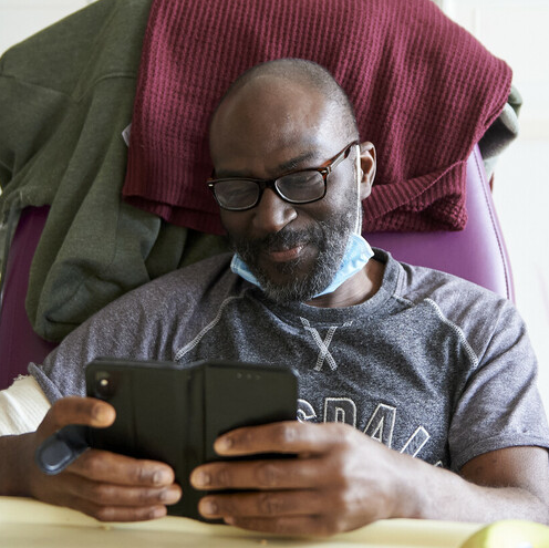 A man in a hospital chair is using his phone