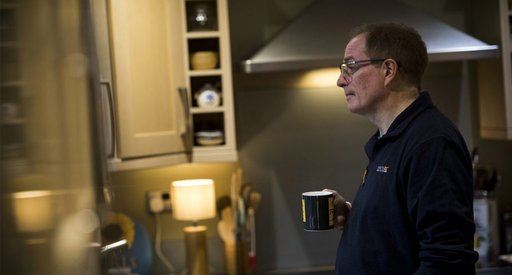 Paul, who lives with chronic myeloid leukaemia (CML), holding a mug, stands in a kitchen