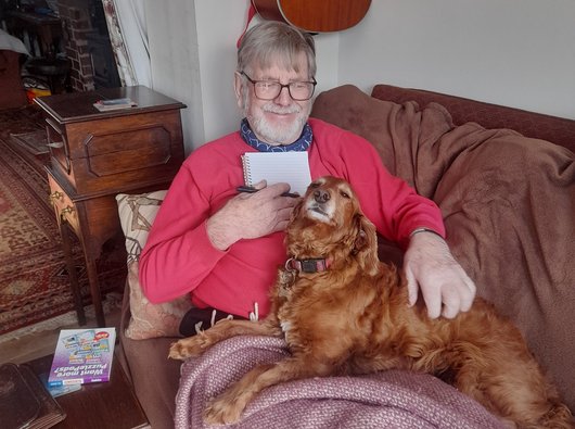 Phil, diagnosed with DLBCL in 2024, sitting on the sofa with his dog.