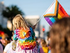 A little girl holds up a Pride flag