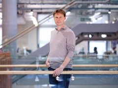 Professor Pavel Tolar stood on a glass walkway in a grand university building looking at the camera