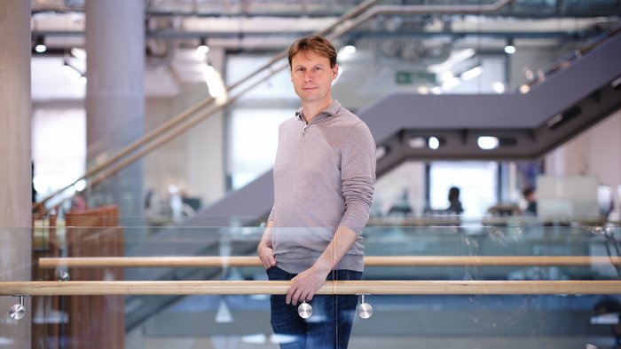 Professor Pavel Tolar stood on a glass walkway in a grand university building looking at the camera