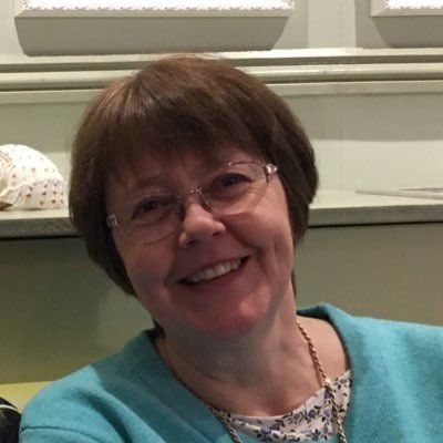 A headshot of a lady with short brown hair and glasses smiling.