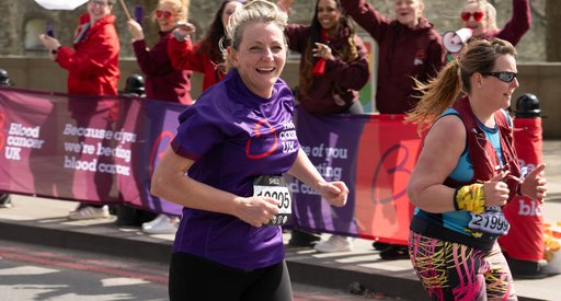 Blood Cancer UK female runner looking to camera with cheer point in the background